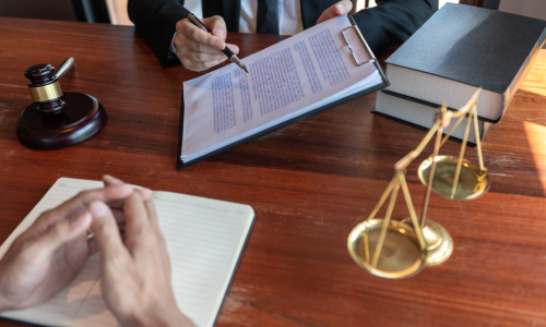 A lawyer presenting a clipboard to a client containing importaint information for a claim.
