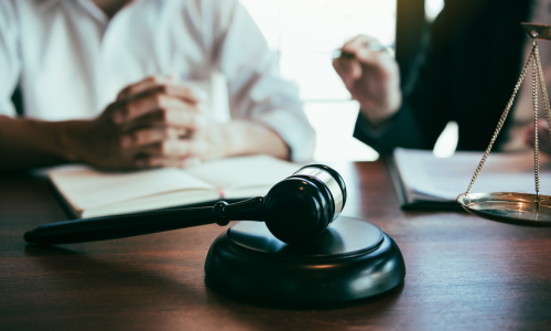 A lawyer and client discussing an approach to a case at a desk in an office.