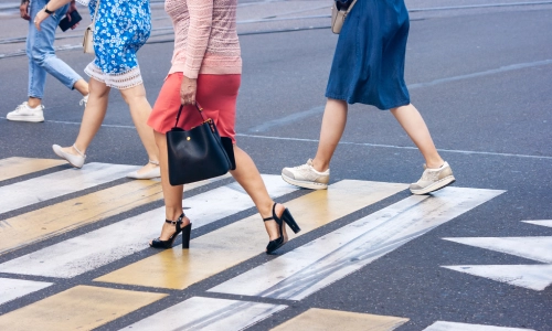 Four pedestrians walking across a crosswalk on a city street, illustrating a potential pedestrian accident scenario.
