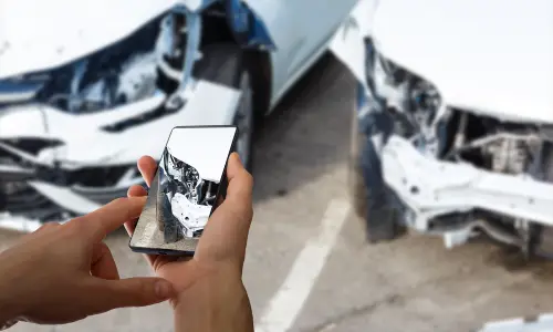 An accident victim taking photos of the point of contact between his car and another after a collision.
