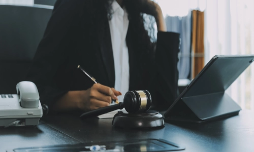 Female attorney reviewing case documents at a desk with a gavel, telephone, and tablet, symbolizing a legal case involving a defective product.