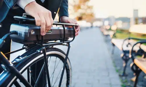 A cyclist adjusting his ride in a park on a sunny afternoon.