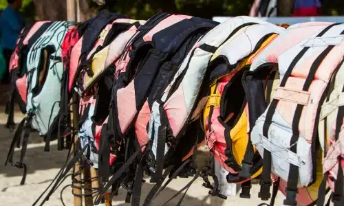 Lifejackets hanging on a fence at the docks late in the day.