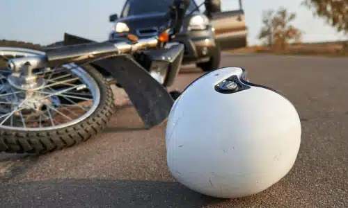 A white motorcyclist's helmet on the ground in front of a tipped over motorcycle.