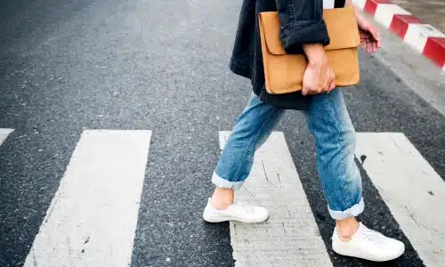 A pedestrian finishing crossing a road and about to step on the sidewalk.
