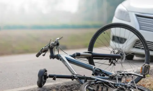 A bicycle lying on the road after being struck by a car.