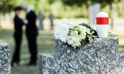 A wrongful death victim's funeral with an urn resting next to flowers and mourning loved ones in the background.