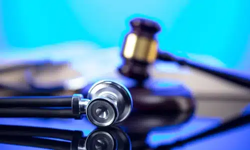 Stethoscope lying beside a judge’s gavel on a reflective surface, representing a Savannah medical malpractice lawyer.