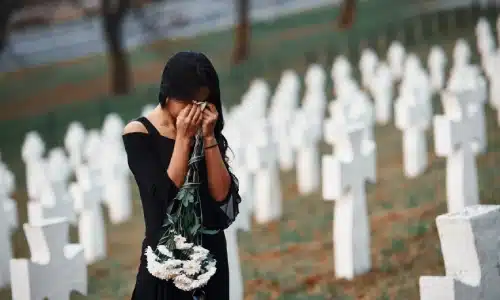 Woman grieving in a cemetery holding white flowers, symbolizing a case for a Savannah wrongful death lawyer.