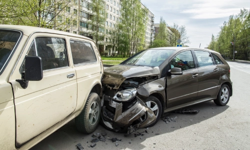 Two vehicles involved in a rear-end collision on a city street, with the front of one car crumpled and debris scattered, illustrating the aftermath of a distracted driving accident.