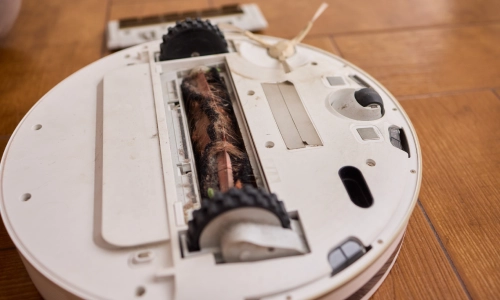 Underside of a dirty robotic vacuum with tangled debris, relevant for a Columbus defective product lawyer.