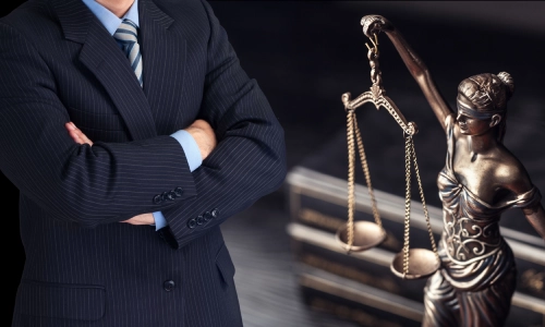 A Gainesville Hit and Run Lawyer standing with arms crossed behind a statue of "Lady Justice"