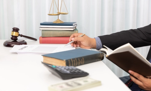 A close up shot of a Gainesville Slip and Fall Lawyer who is signing documents while holding a notebook in the left hand.