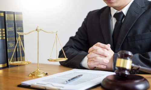 A truck accident lawyer sitting at a desk with both hands together on the table inside a Gainesville law office.