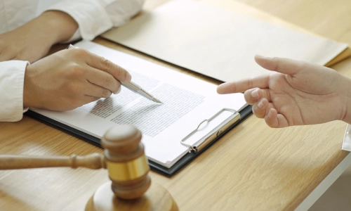 A Gainesville Wrongful Death Lawyer pointing at documents while showing them to a client while both are sitting in a law office.