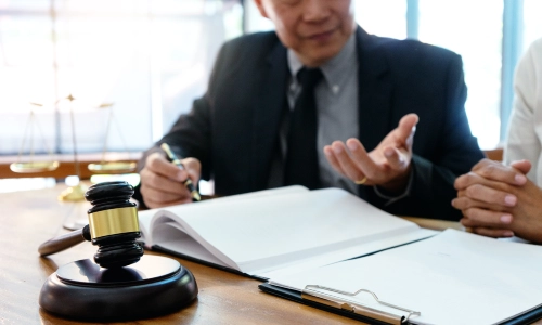 A Daycare Injury Lawyer speaking with a client who is sitting beside him while they go over case files on a table in a Houston law office