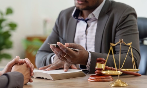An uber accident lawyer gestures with a pen in his left hand while speaking with a client inside a Houston law office
