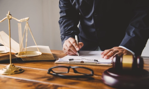 A wrongful death lawyer is standing up inside a Houston law office while signing documents