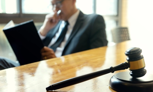 A bycicle accident lawyer is sitting inside an Arizona law office with one hand covering his mouth while reading a case file