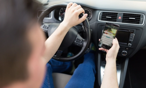 Rear view of a man who is driving in Arizona while distracted by texting on his cellphone