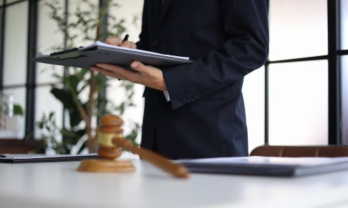 A personal injury lawyer is standing up while holding a clipboard with files in one hand inside an Arizona law office.