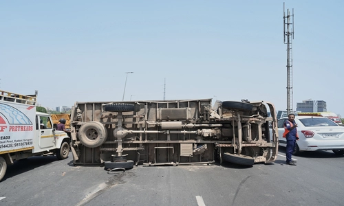 A photo of a truck overturned on the roadway after a rear tire burst, causing traffic congestion.