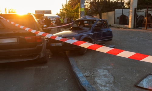 A car accident occurred on a city street, where vehicles crashed during a traffic incident, leaving damaged cars after the collision, with red and white police tape securing the scene.