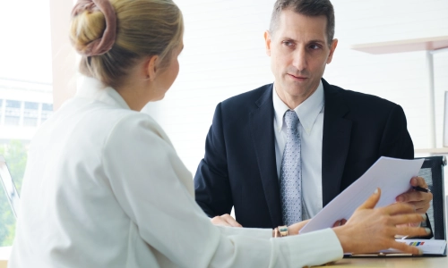 An Arizona medical malpractice lawyer is speaking with a medical expert to review details related to his client’s malpractice case.