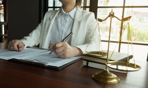 A Lyft accident lawyer who is wearing a white suit signing documents on their table in their California law office