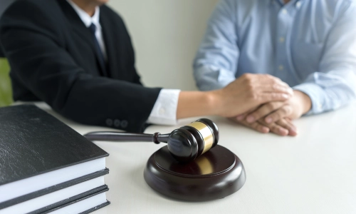 A medical malpractice lawyer comforting a male client by placing his hand on theirs while discussing a case in a California law office.