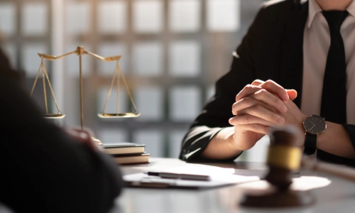 A California negligence lawyer and their colleague discussing a case while sitting opposite of each other in their law office.