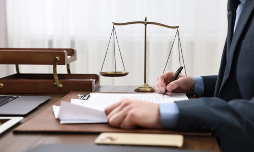 A pedestrian accident lawyer signing files on top of a wooden table inside a California law office.