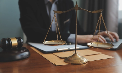 A slip and fall lawyer typing on a laptop while reading printed documents on an office table inside a California law office.