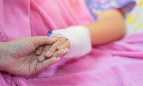 A mother holding the hand of her young child, who wears a bandage for her injured hand while awaiting the help of a California daycare injury lawyer.