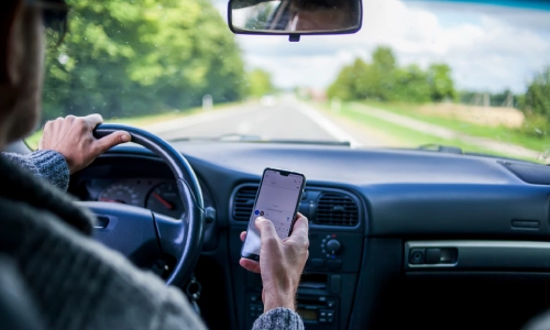 A photo of a driver dangerously using a phone while driving.