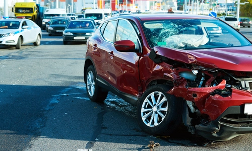 A photo shows a car with visible damage on the road after a collision.
