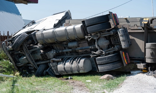 A photo a truck is lying on its side in a car accident on the highway.