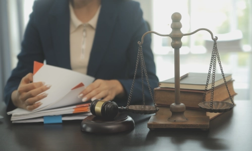 A female Riverside Bicycle Accident Lawyer is flipping pages of a legal document as she sits in her law office.