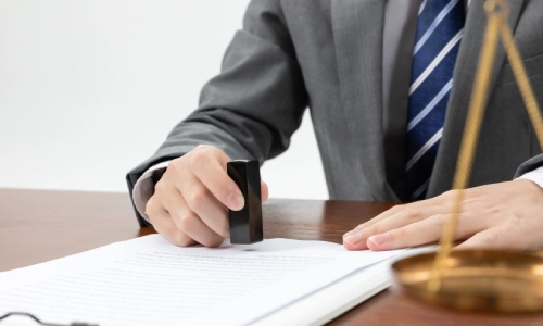 A male hit-and-run lawyer sitting in a Riverside law office stamping documents on an office table