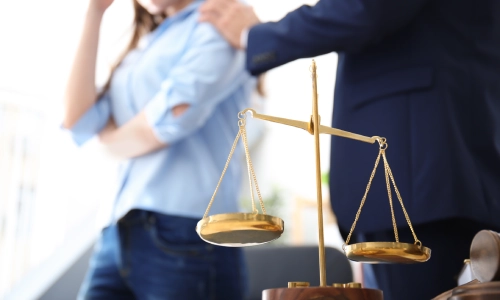 A medical malpractice lawyer serving Riverside is comforting a client while standing in a law office with scales of justice in closer view