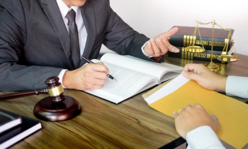 A Riverside Negligence Lawyer gestures with his left hand while speaking with a client inside a law office.