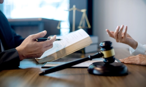 A Riverside Rideshare Accident Lawyer holds a law book while having a discussion with a colleague