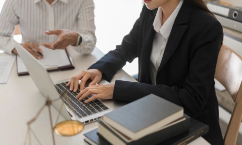 A Tempe premises liability lawyer working on her laptop while speaking with her client about her legal claims.