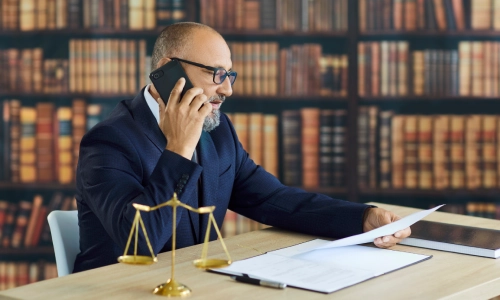 A Tempe truck accident lawyer speaking with a client on the phone while reviewing documents.