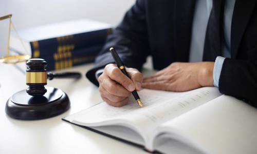 A Tucson Lyft accident lawyer is writing notes, with a gavel hammer and a few law books beside him.