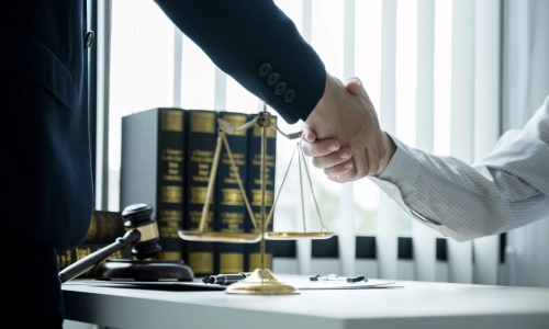 A Tucson Pedestrian Accident Lawyer is standing up whila shaking the hand of a client who is wearing white