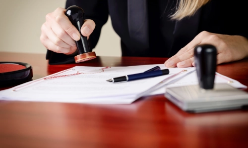 A Tucson slip and fall lawyer sits in front on an office desk while notarizing documents with a stamp in hand