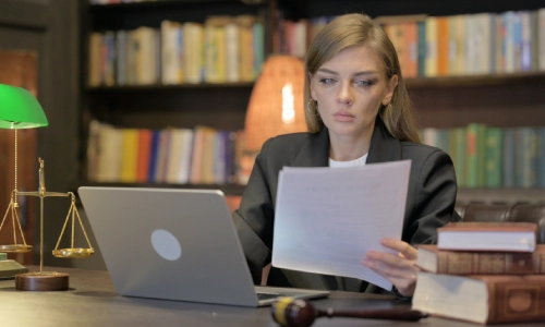 A Tucson brain injury lawyer is reviewing the injury claim she drafted for her client in front of her laptop with a gavel hammer and a few law books beside her.