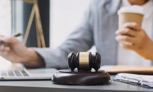 An Acworth negligence lawyer holding a cup of hot coffee with a gavel beside her on the table.