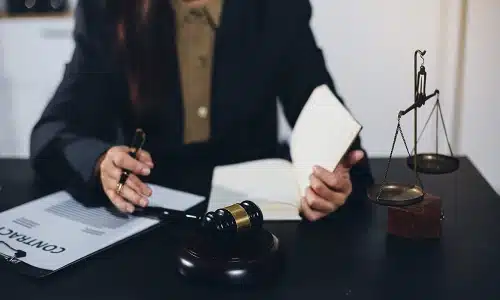 A photo of a Long Island defective product lawyer signing a document with a gavel beside him.